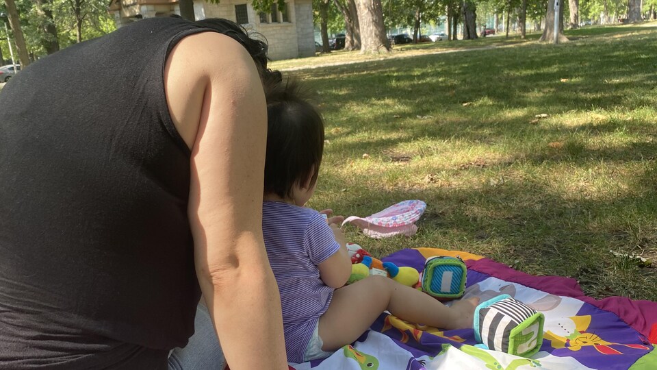 Une mère et son enfant sur une couverture dans un parc.