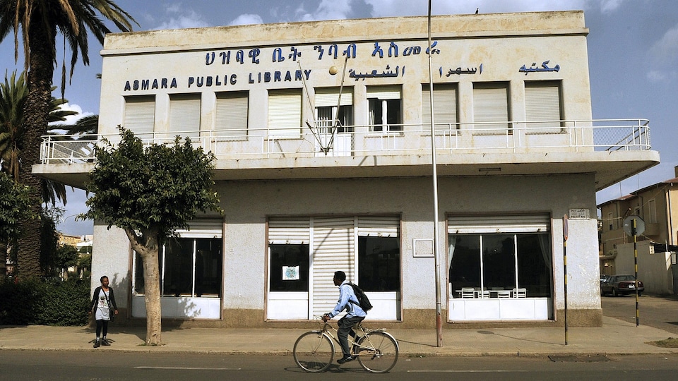 Un homme à vélo devant une bibliothèque publique d'Asmara. 