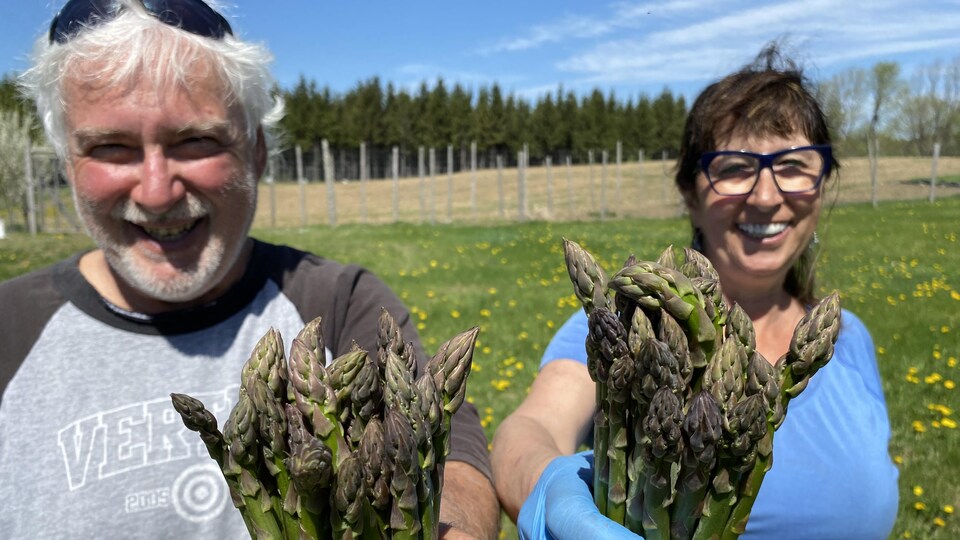Les deux producteurs souriant avec des asperges dans les mains.
