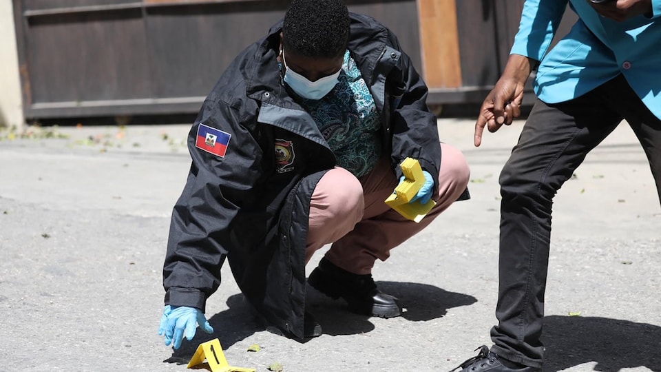 Un policier agenouillé marque un élément de preuve au sol.