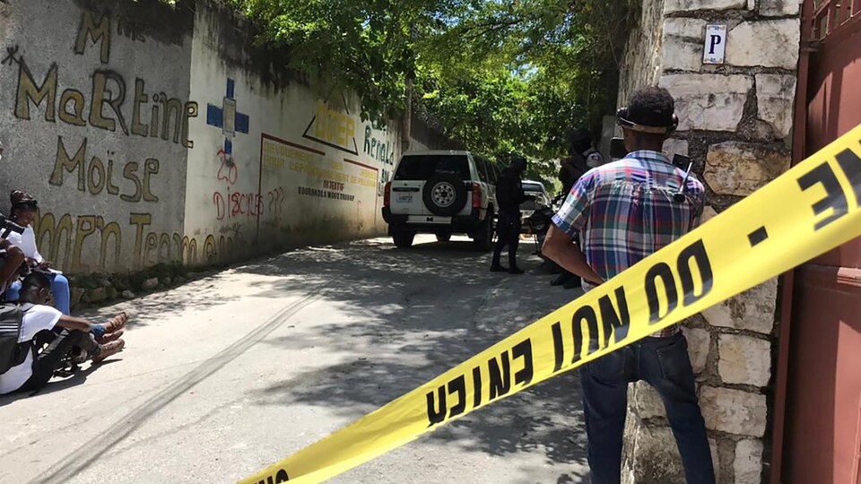 Un homme se tient à côté d'un cordon de sécurité, dans la rue. 