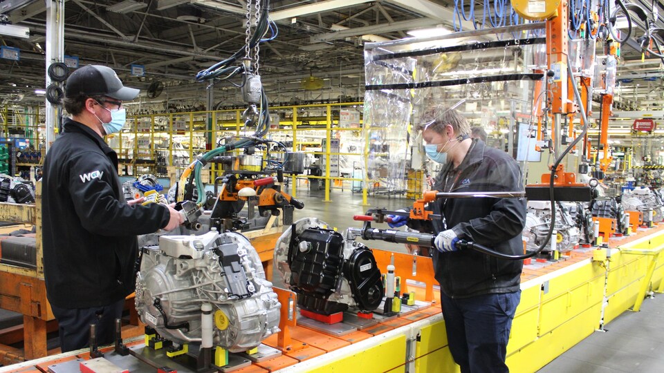 Des employés de Fiat Chrysler portant des masques travaillent sur une chaîne de montage.