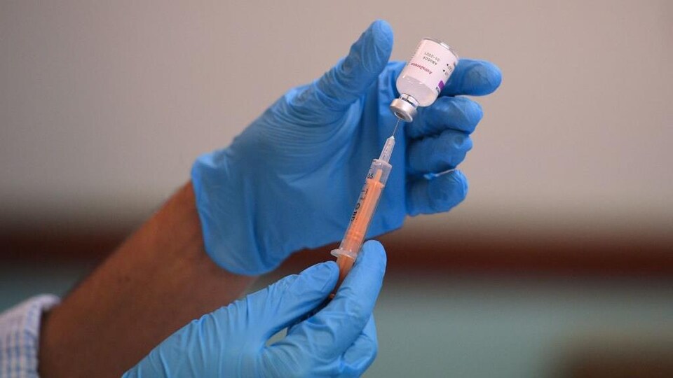 Une personne extrait une dose d'un vaccin contre la COVID-19 d'une fiole.