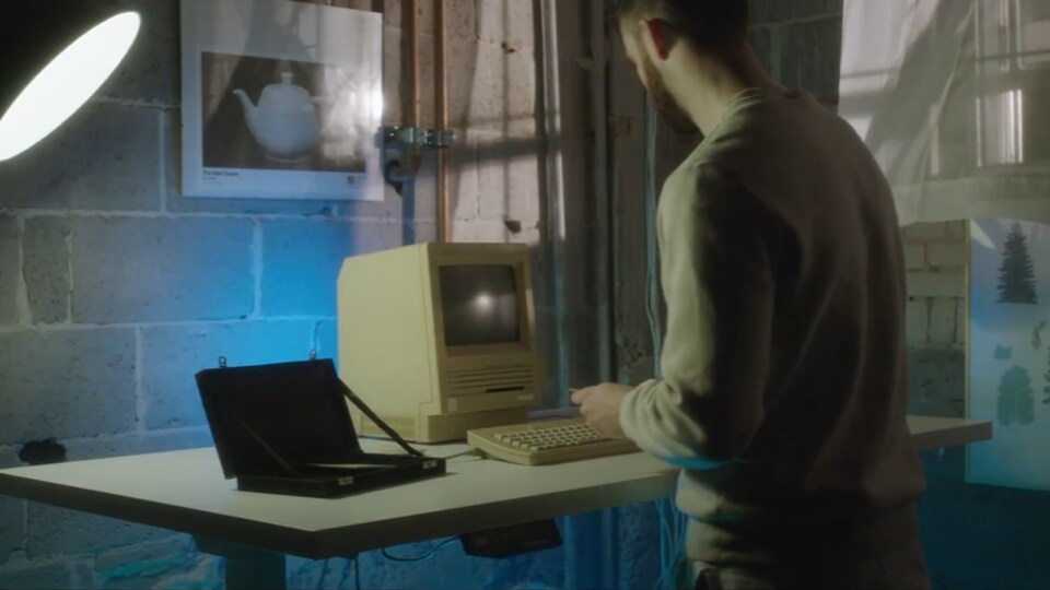Un homme met une disquette dans un vieil ordinateur. 