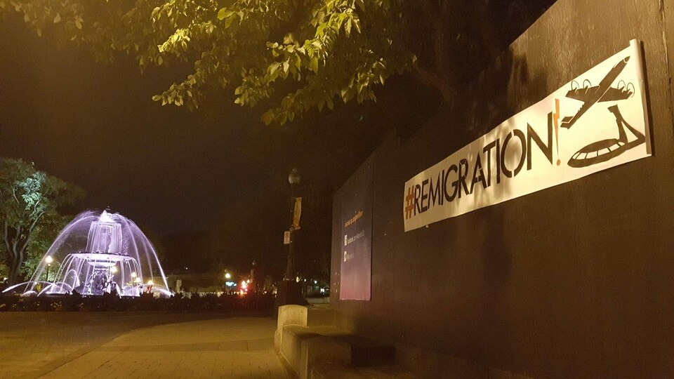Une affiche « #remigration » à côté de la fontaine de Tourny