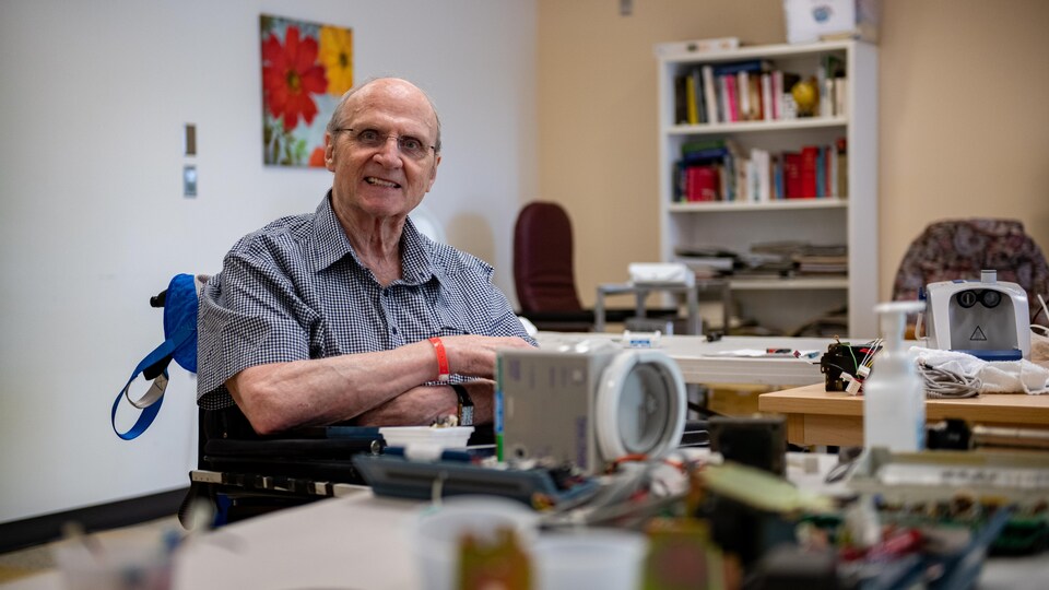 Michel Bonneau, souriant, qui démonte un appareil médical
