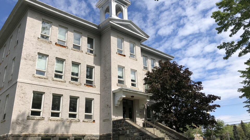 Une ancienne école avec un clocher.