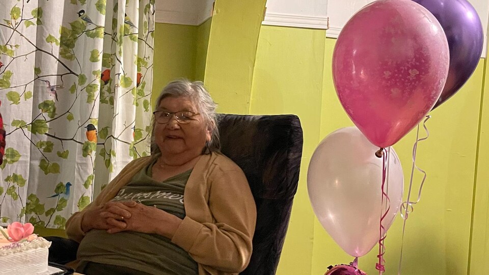Une vieille dame avec des ballons d'anniversaire et le chiffre 81