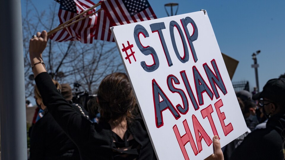 Une personne tient une pancarte sur laquelle est écrit : Stop Asian Hate.