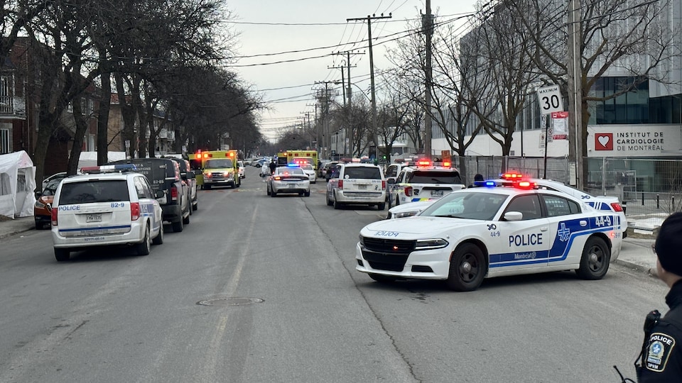 De nombreuses voitures de police bloquent une rue de Montréal.