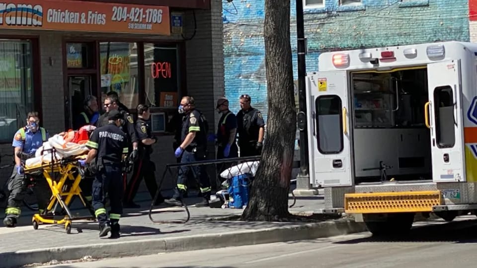 Des agents de police et des ambulanciers mettent l'adolescent dans une ambulance.