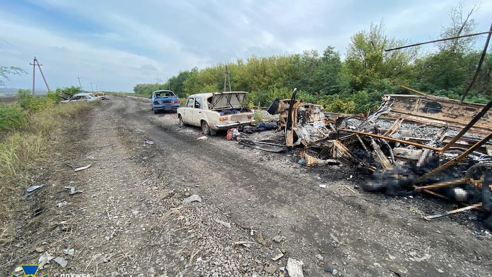 Un convoi de voitures détruites sur le bord de la route avec des cadavres carbonisés à travers les débris. 