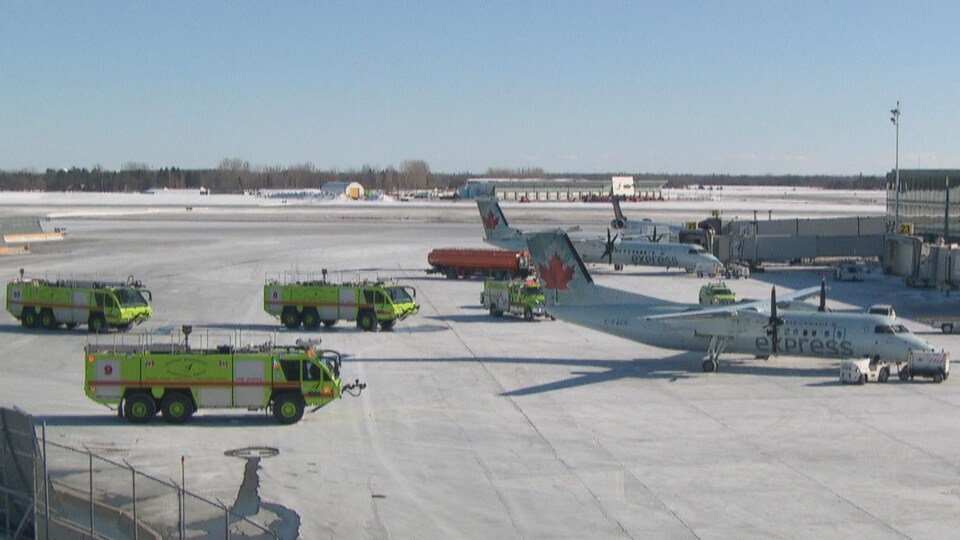 Un avion sur le tarmac de l'aéroport d'Ottawa, entouré de véhicules de secours.