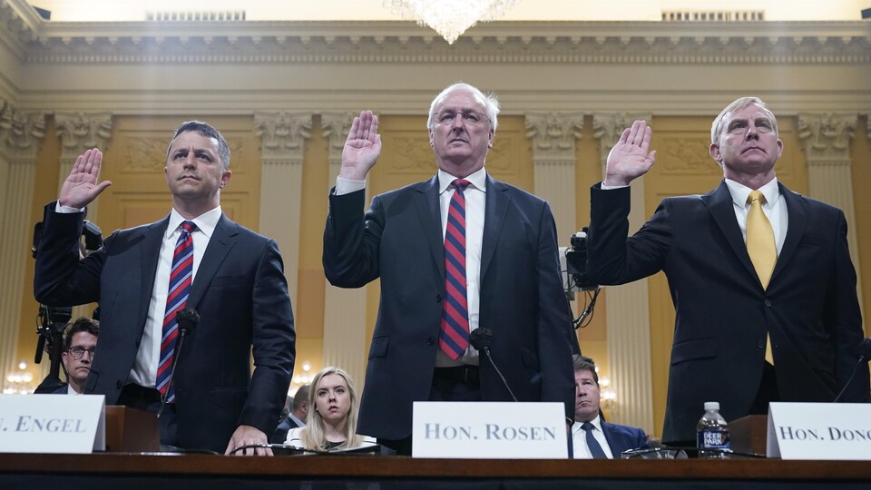 Les trois hommes lèvent la main droite pour prêter serment.