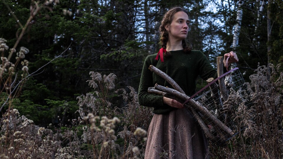 Exemple d'autoportrait narratif en couleur réalisé par Audrée Wilhelmy, écrivaine et photographe, la représentant dans la forêt tenant un panier métallique contenant du bois ramassé.