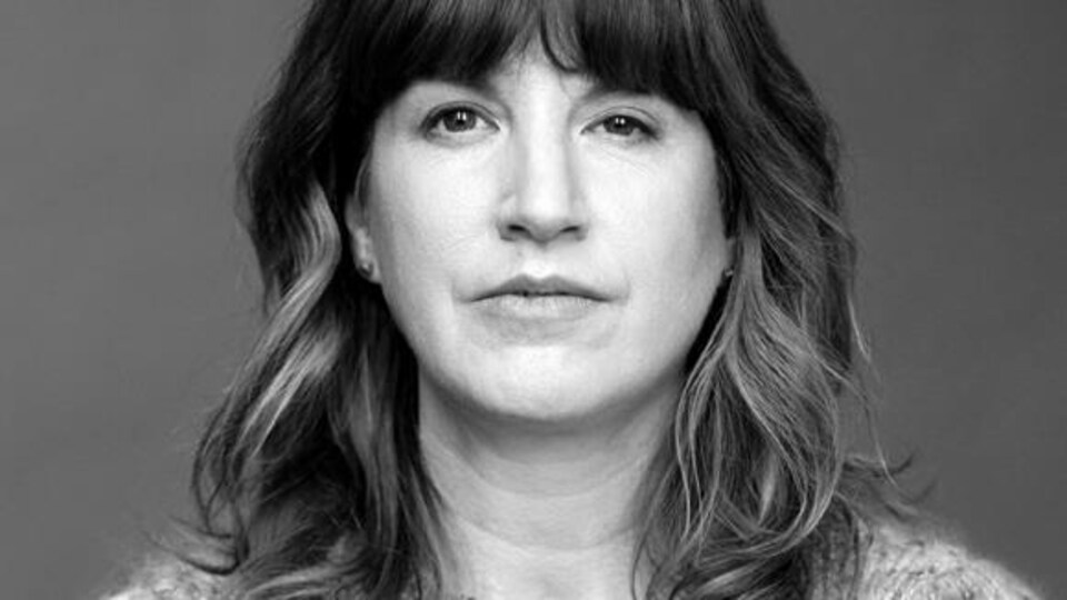 L'actrice regarde devant d'un air impassible. Son visage est légèrement asymétrique.