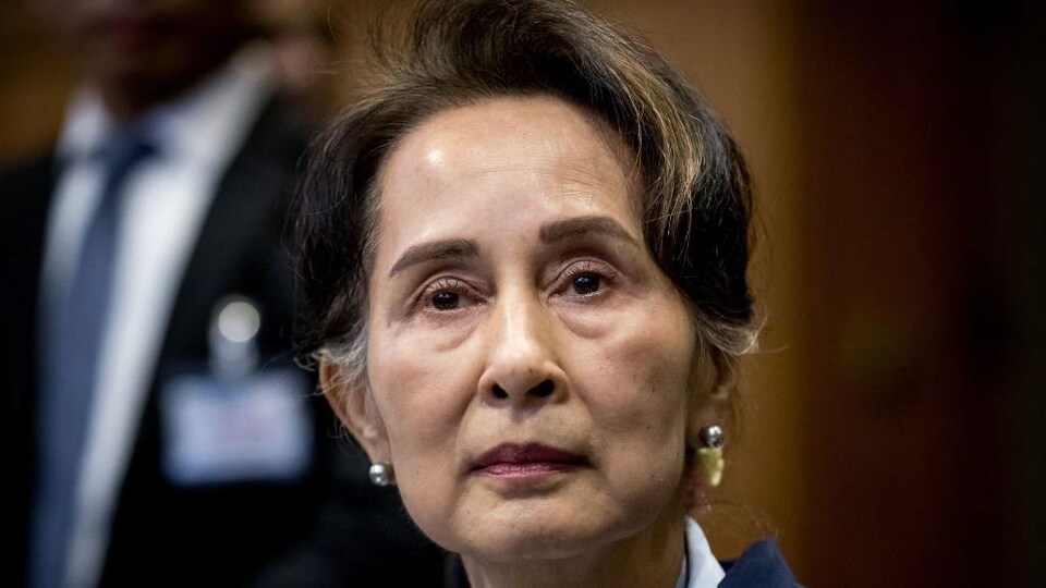 Plan rapproché sur le visage d'Aung San Suu Kyi, qui regarde au loin, l'air sérieux.