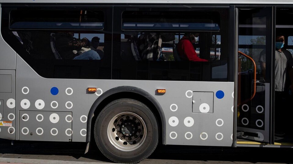 Une passagère portant un masque s'apprête à descendre d'un autobus municipal à Brampton.