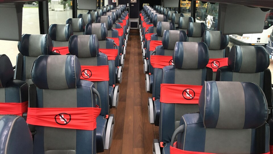 Des sièges entourés de rubans rouges dans un autobus.