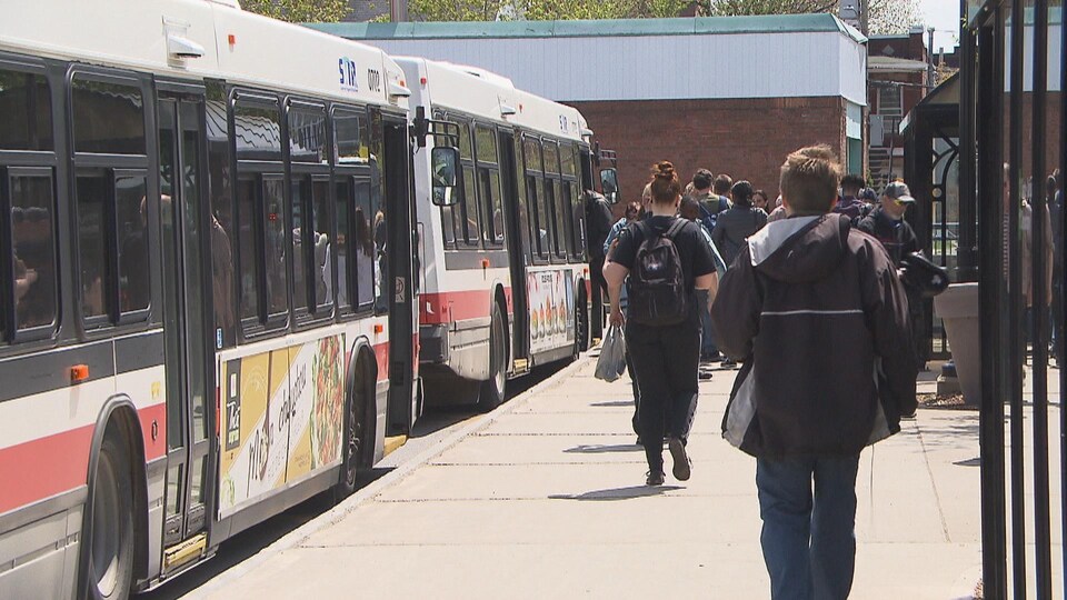 Des gens sur le quai qui embarquent dans des autobus au terminal du centre-ville de Trois-Rivières.