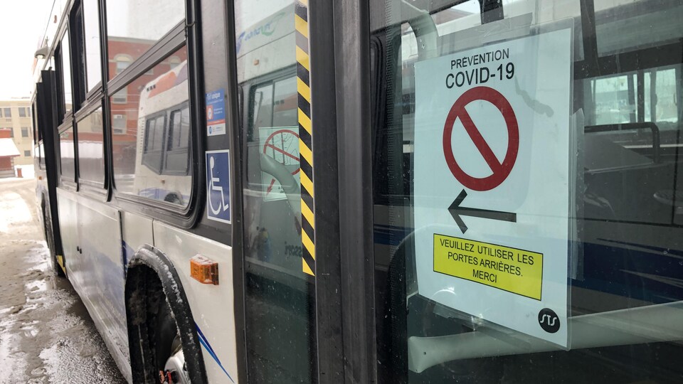 Une affiche invite les passagers à utiliser les portes arrières à l'entrée de l'autobus.