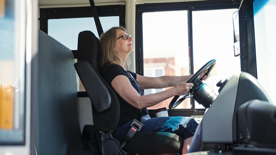 Une femme assise au volant d'un autobus scolaire.