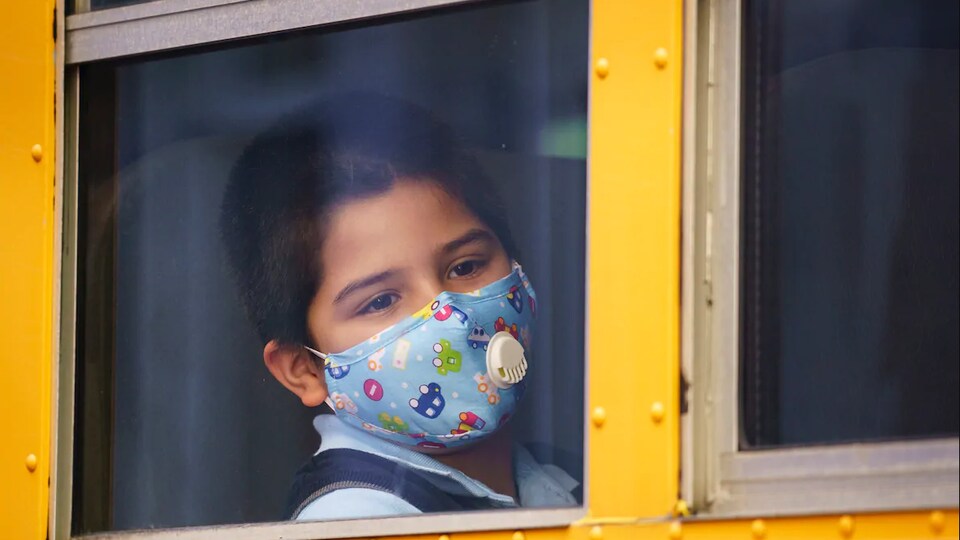 Un élève portant un masque dans un autobus scolaire.