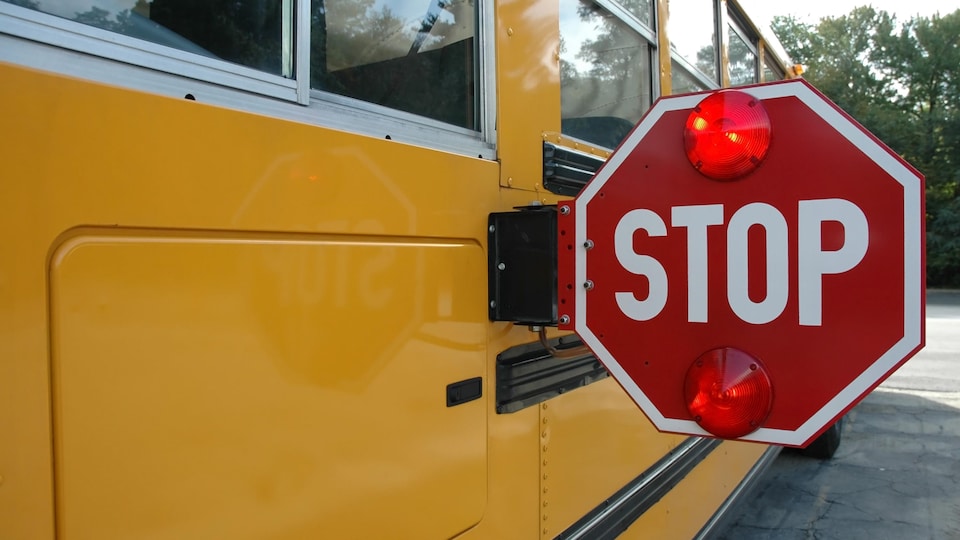 Signal Stop clignotant sur un autobus scolaire.