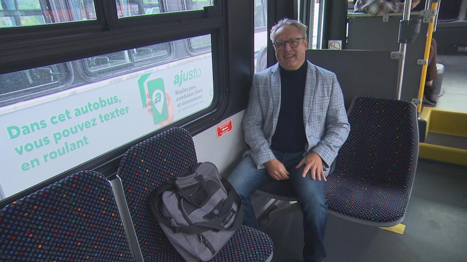 Claude Bouchard est assis dans un autobus.