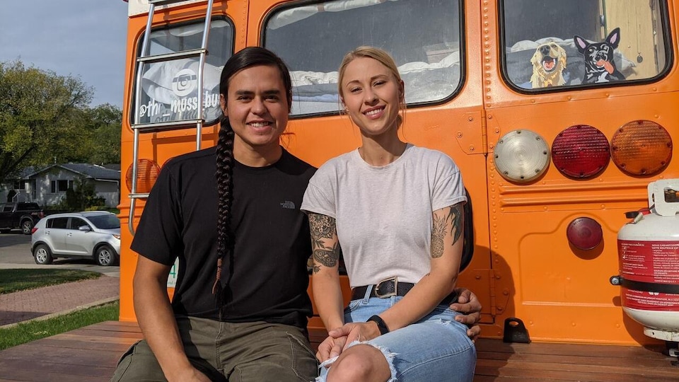 Shanny Kirby et Karlen Janiver sint assis sur une plateforme à l'arrière de leur autobus.