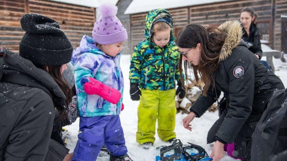 Des adultes aident des tout-petits à mettre leurs raquettes.