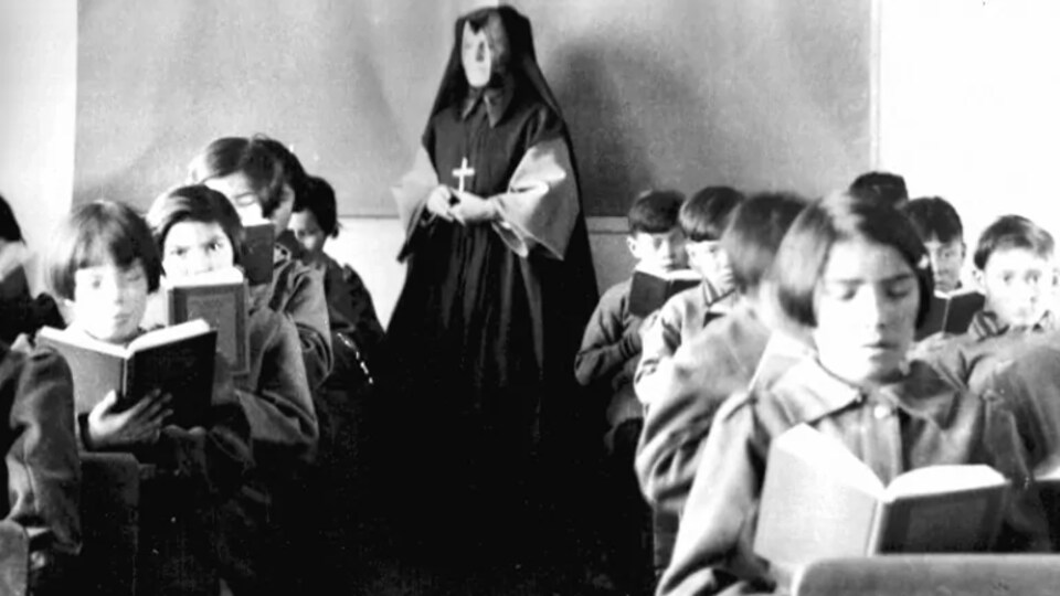 Photo historique dans une classe du pensionnat Sainte-Anne où l'on peut voir des jeunes Autochtones en train de lire et une religieuse au fond de la pièce.