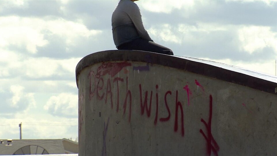 Un jeune est assis sur une structure en ciment.