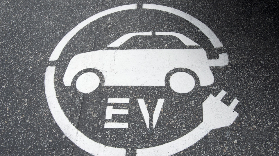 Symbole de borne de recharge pour voiture électrique peint sur la chaussée.