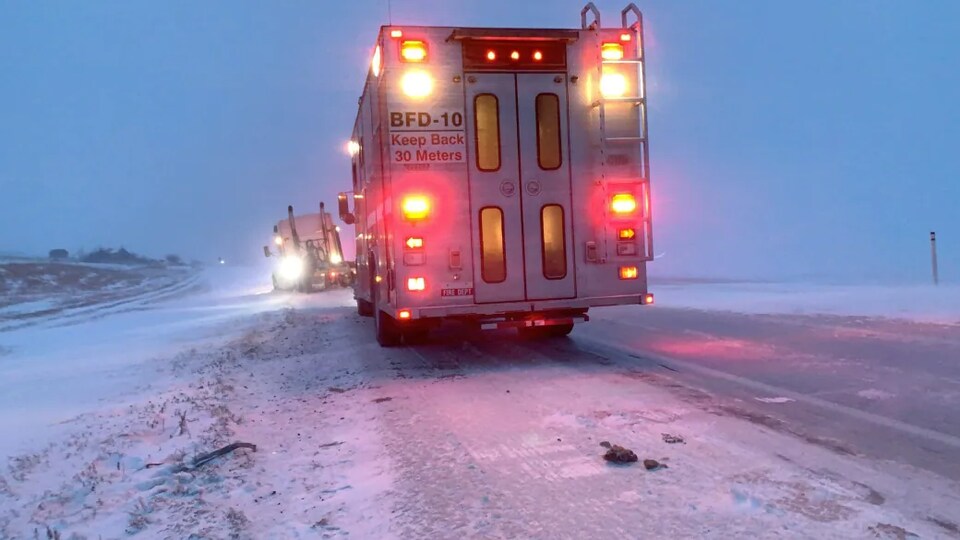 Un camion de pompiers sur la route vient en aide à un semi-remorque qui a effectué une sortie de route.