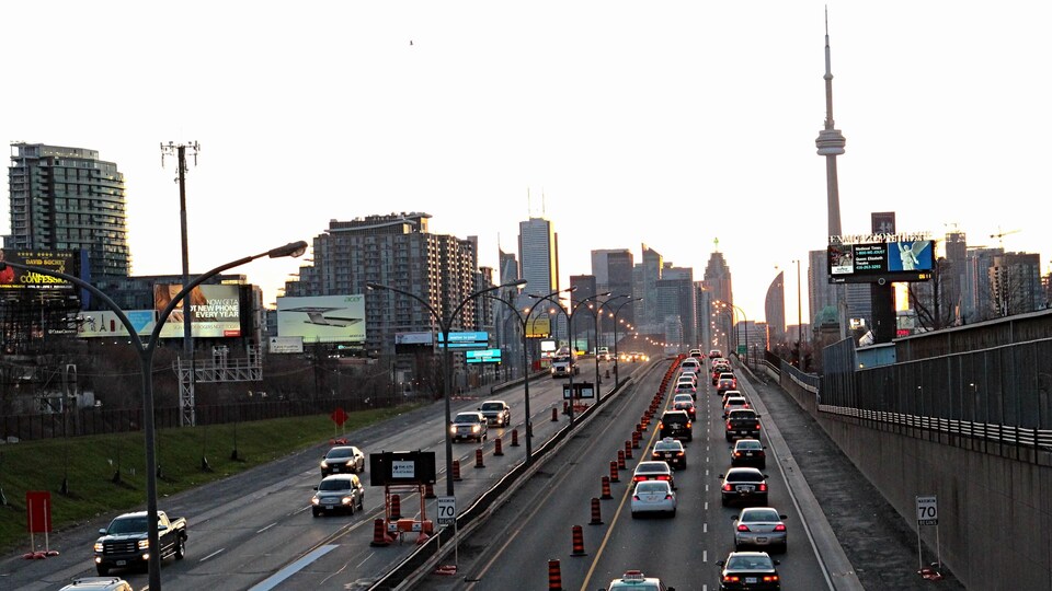 Une autoroute à quatre voies avec le centre-ville de Toronto en arrière-plan.