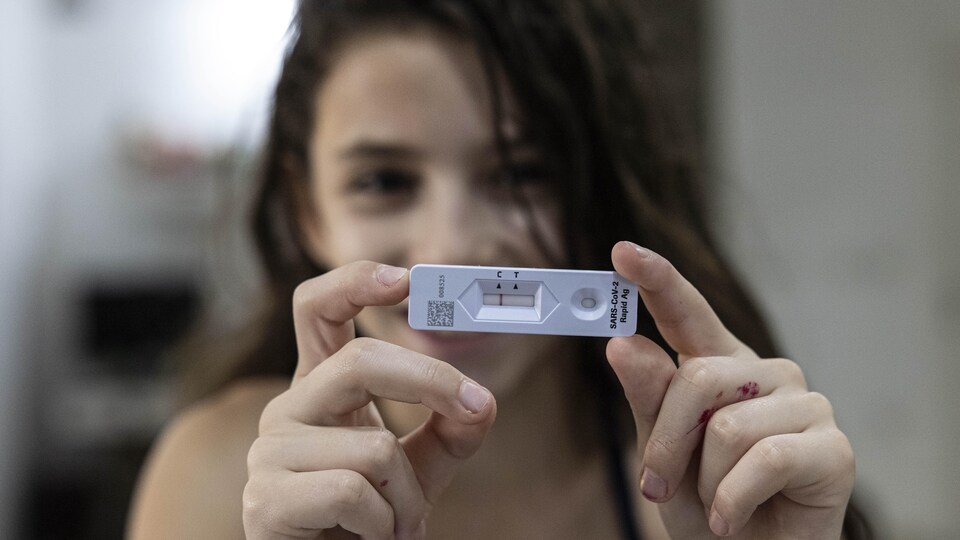 Une jeune fille exhibe la cartouche sur laquelle apparaît son résultat négatif à un test de dépistage de COVID-19 effectué à la maison.