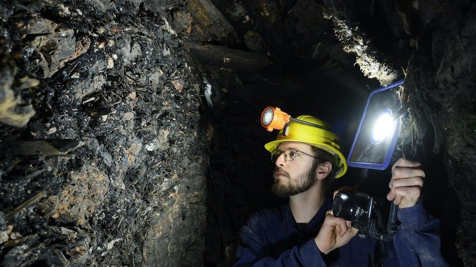 Un chercheur inspecte le mur d'une mine.