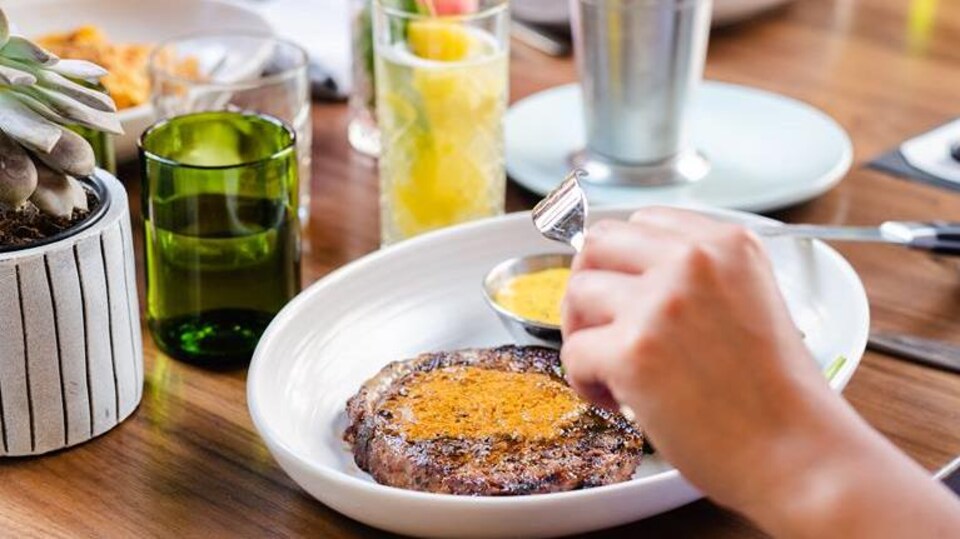 Des clients mangent de la viande et des frites à une table.