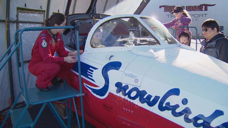 Une femme dans un avion et une jeune fille qui veut s'y monter à bord du poste de pilotage