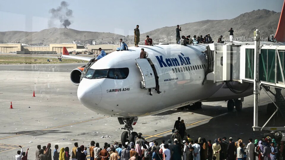 Dozens of people were waiting in front and aboard a plane at Kabul airport.