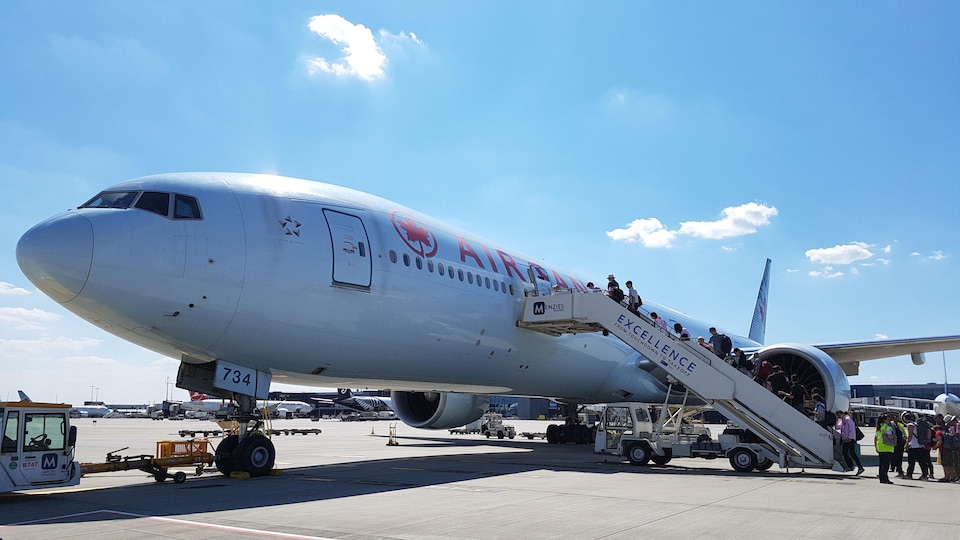 Des passagers montent dans un Boeing 777 d'Air Canada, sur le tarmac de l'aéroport Heathrow, à Londres.