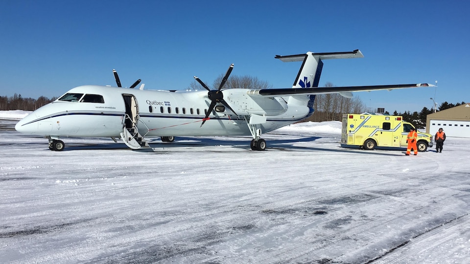 Un avion-ambulance et une ambulance sur la piste de l'aéroport de Matane en hiver.