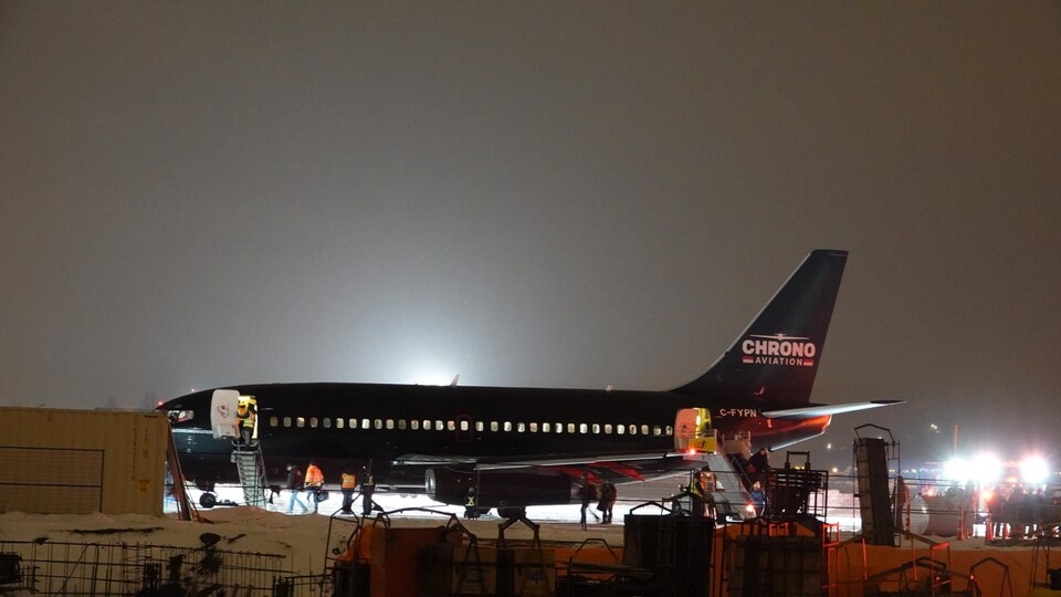 Un avion de la compagnie Chrono sur la tarmac de l'aéroport, la nuit.