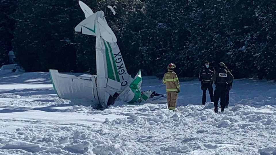 Des policiers se tiennent près d'un petit avion qui s'est écrasé sur un lac.