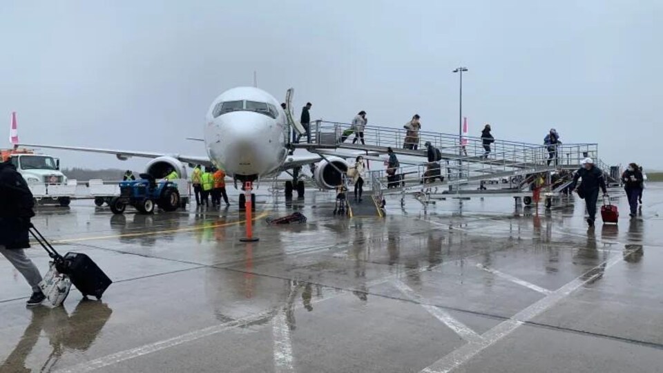 Un avion sur le tarmac, des passagers descendent de l'avion.