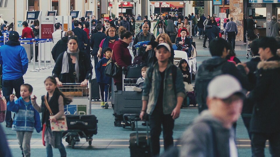 File de personnes qui marchent dans un aéroport. 