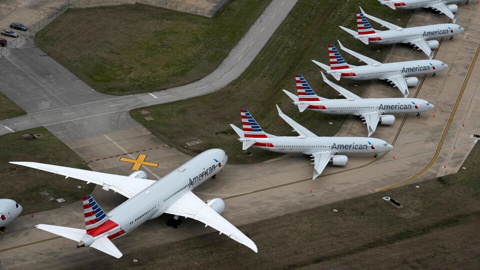 Des avions inutilisés ont été stationnés le long d'une piste d'aéroport.