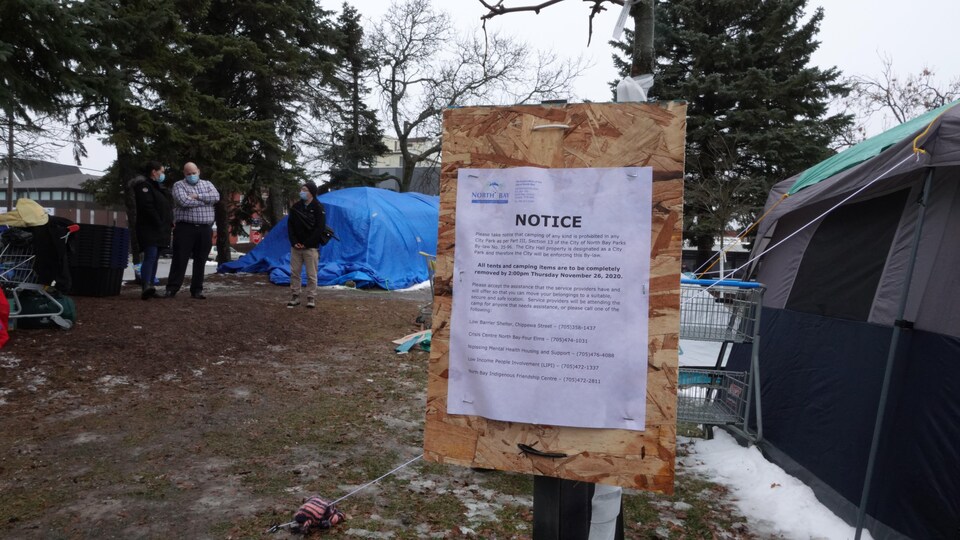 Un avis officiel de la Ville affiché près d'une tente.