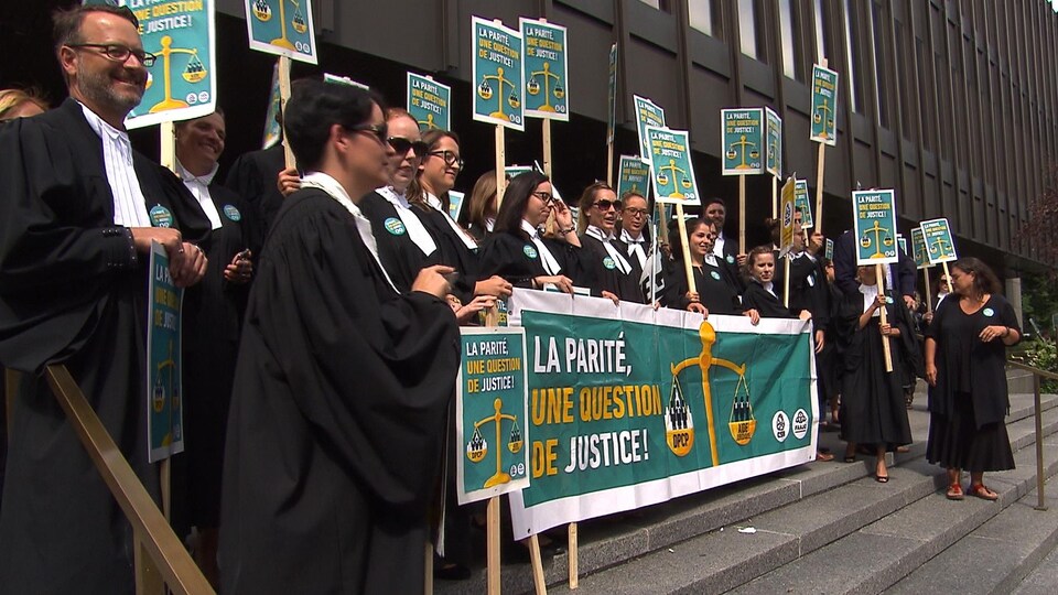 Des avocats brandissent des pancartes sur les marches du palais de justice.
